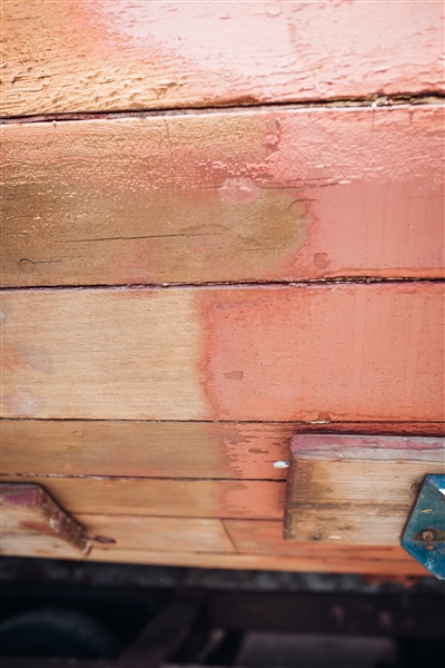 A close-up of a wooden surface showing a section partially cleaned or treated, with a visible contrast between the untreated and treated areas.